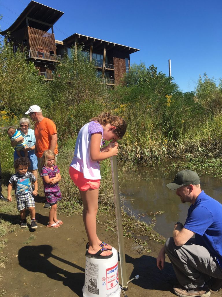 A curious visitor uses a turbidity tube to test the clarity of the pond water. 